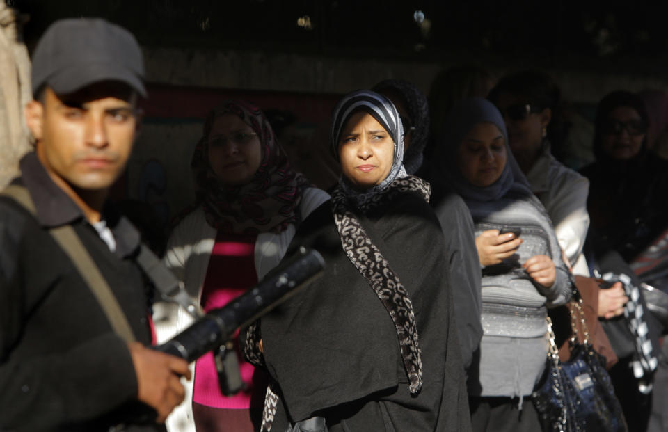 An Egyptian policeman stands guard as voters line up to vote outside a polling station in Cairo, Egypt, Tuesday, Jan. 14, 2014. Egyptians are voting on a draft for their country's new constitution that represents a key milestone in a military-backed roadmap put in place after President Mohammed Morsi was overthrown in a popularly backed coup last July. (AP Photo/Amr Nabil)