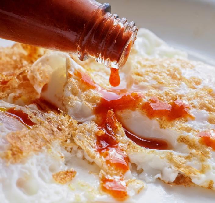 hot sauce being poured on eggs
