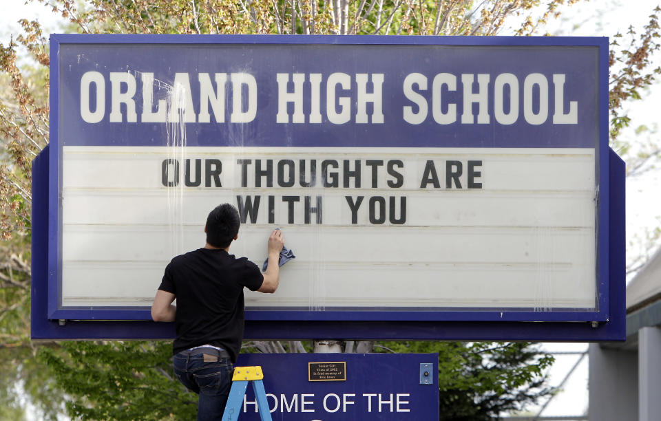 Sergio Parra, 16, a 10th grader at Orland High School, cleans the glass on the school's sign, Friday, April 11, 2014, after placing a memorial remembering the victims of a fiery crash between a tour bus and a FedEx truck in Orland, Calif. Ten people were killed and dozens injured in the fiery crash that happened Thursday, between the truck and a bus carrying high school students on a visit to a Northern California college. Orland High is across the street from where a Red Cross shelter was setup to handle some of survivors of the accident. (AP Photo/Rich Pedroncelli)