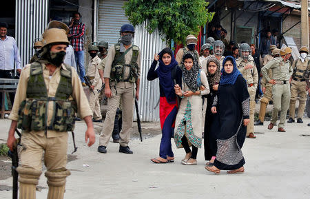 Women walk past police officers during clashes with stone pelters in Srinagar, Kashmir, India May 17, 2017. REUTERS/Cathal McNaughton