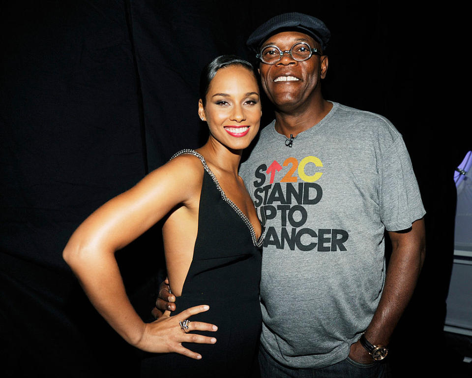 Alicia Keys in a sleeveless dress and Samuel L. Jackson in a "Stand Up To Cancer" t-shirt pose together, smiling at an event