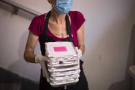 A volunteer wears a protective face mask to help curb the spread of the coronavirus as she holds packs of food in Lasova, a non profit origination that provides food and shelter for the homeless, in Tel Aviv, Israel, Thursday, July 9, 2020. With a new outbreak of coronavirus devastating Israel's economy, one of Prime Minister Benjamin Netanyahu's closest confidants was dispatched on to a TV studio on a recent day to calm the nerves of a jittery nation. Instead, he dismissed the public's economic pain as "BS." (AP Photo/Ariel Schalit)