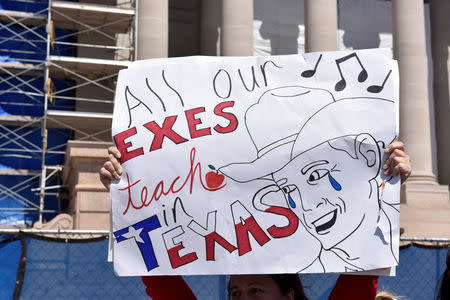 A teacher waves a sign lamenting the loss of Oklahoma teachers to Texas outside the state Capitol on the second day of a teacher walkout in Oklahoma City, Oklahoma, U.S., April 3, 2018. REUTERS/Nick Oxford