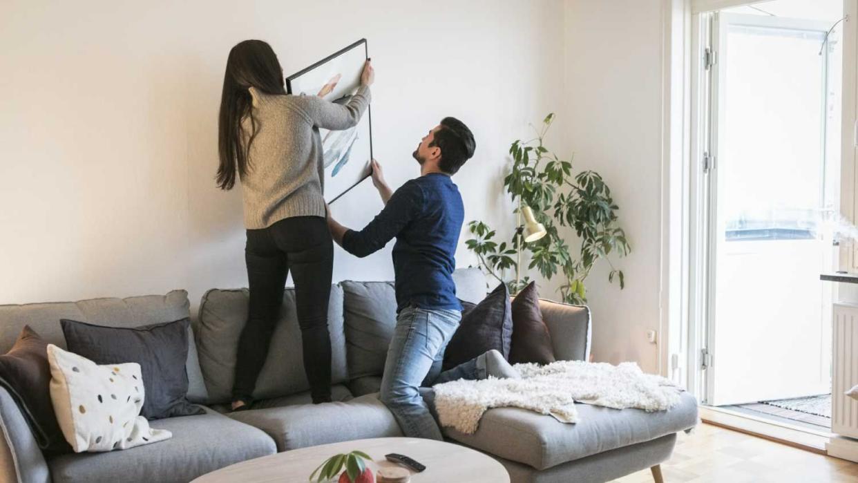 Couple adjusting painting on wall