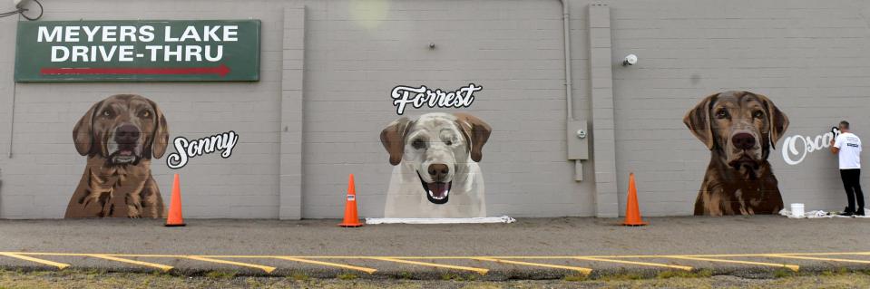 Artist and owner of Untitled Painting Co. Josh Humm creates a mural of TJ Sliman’s dogs on the side of his family business, Meyers Lake Beverage and Drive Thru in Canton.