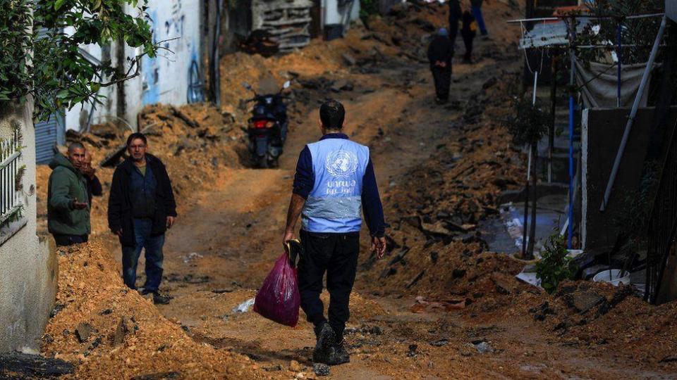 Un hombre con un chaleco de la UNRWA camina por una calle arrasada por las fuerzas israelíes en Yenín, en Cisjordania. 