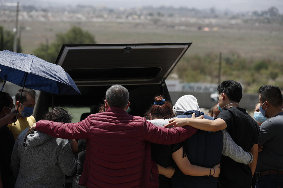 Family members gather to mourn at the back of the hearse, as they prepare to bury a woman who died of suspected COVID-19, in a section of the Municipal Cemetery of Valle de Chalco opened to accommodate the surge in deaths amid the ongoing coronavirus pandemic, on the outskirts of Mexico City, Thursday, July 2, 2020. (AP Photo/Rebecca Blackwell)