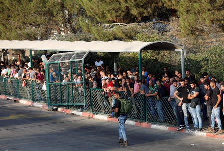 FILE PHOTO: An Israeli security guard walks as Palestinian workers wait to cross into Barkan industrial zone that is adjacent to the settlement of Barkan, in the occupied West Bank October 9, 2018. REUTERS/Mohamad Torokman/File Photo