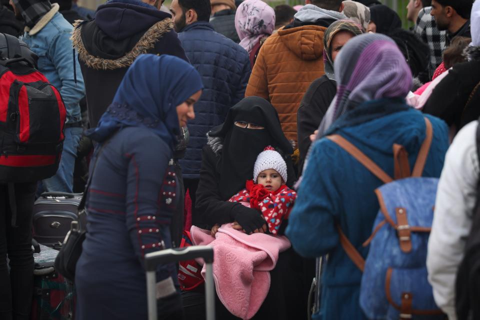 Syrians wait to cross into Syria from Turkey at the Cilvegozu border gate, near the town of Antakya, southeastern Turkey, on Tuesday.