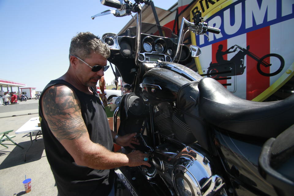 Chris Cox, the founder of Bikers for Trump, examines his motorcycle on Saturday, Aug. 8, 2020, outside the Bikers for Trump trailer he brought to the Sturgis Motorcycle Rally, in Sturgis, S.D. The group has taken advantage of recent motorcycle rallies, which have been some of the largest mass gatherings in the country, to make direct appeals to register to vote. While the group has gained a significant online following for its shows of bravado, it remains to be seen if they can get ballot boxes filled with bikers, many who hail from the suburbs. (AP Photo/Stephen Groves)