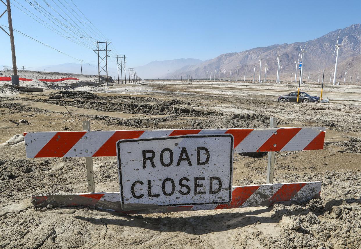 A road closed sign is buried in mud after recent rains flooded the road at the Whitewater River in Palm Springs, Calif., August 24, 2023.