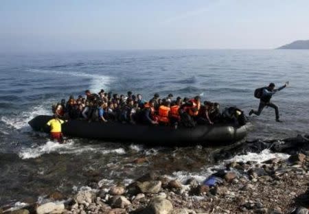 An Afghan migrant jumps off an overcrowded raft onto a beach at the Greek island of Lesbos, October 19, 2015. REUTERS/Yannis Behrakis