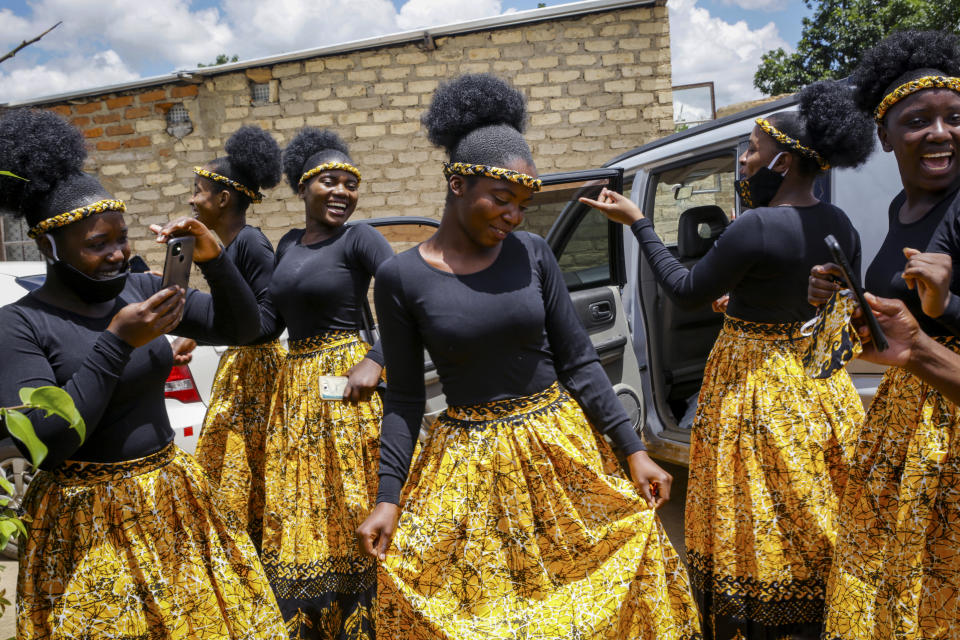 Bridesmaids share a joke as they dance at a traditional marriage ceremony in the capital Harare, Zimbabwe Saturday, March 6, 2021. Many people across Africa are rethinking big, bountiful weddings amid the economic ravages of COVID-19 and the coronavirus pandemic is forcing change in communities where family can mean a whole clan and weddings are seen as key in cementing relations between communities. (AP Photo/Tsvangirayi Mukwazhi)