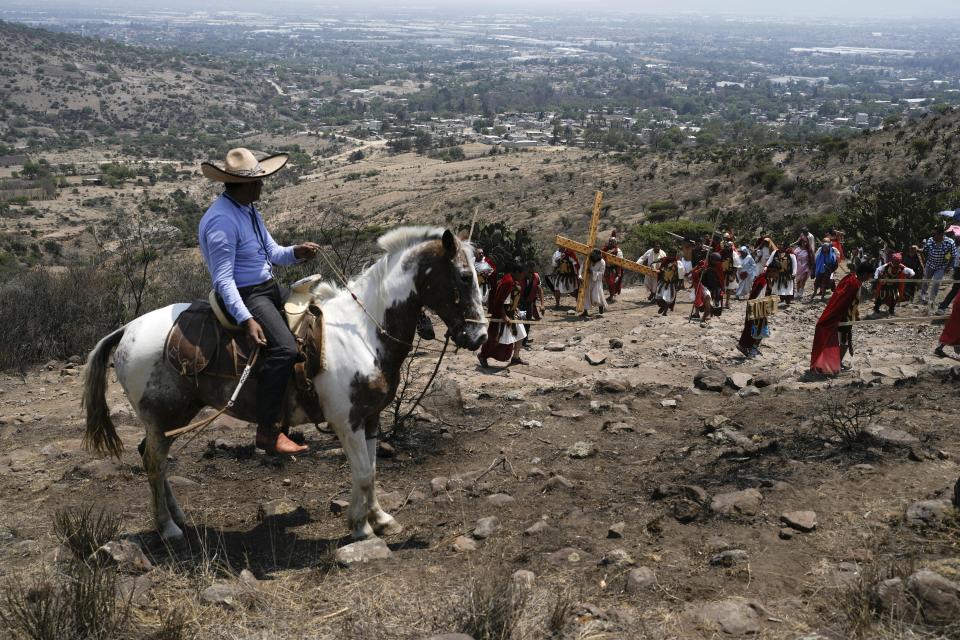 A man on horseback watches a Way of the Cross reenactment, as part of Holy Week celebrations in the San Mateo neighborhood of Tepotzotlan, Mexico, Friday, March 29, 2024. Holy Week commemorates the last week of Jesus Christ's earthly life which culminates with his crucifixion on Good Friday and his resurrection on Easter Sunday. (AP Photo/Marco Ugarte)
