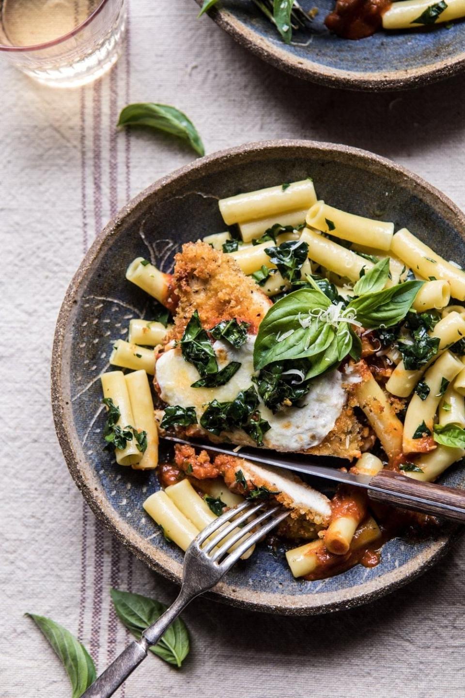 Plate with pasta, tomato sauce, basil, and breaded chicken, fork on side