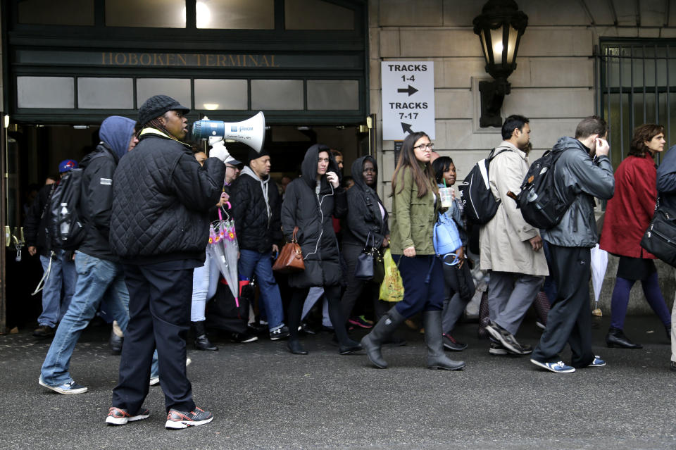 A transit official directs crowds with a megaphone at Hoboken Terminal in Hoboken, N.J., Tuesday, April 4, 2017. A minor derailment on Monday at Penn Station involving a New Jersey Transit train and other rail issues are causing major problems for New York City metro area commuters. (AP Photo/Seth Wenig)