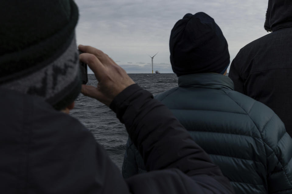 Guests observe the first operating South Fork Wind farm turbine, Thursday, Dec. 7, 2023, 35 miles east of Montauk Point, N.Y., during a tour organized by Orsted. The turbine at the commercial-scale offshore wind farm is producing power for the U.S. electric grid for the first time. (AP Photo/Julia Nikhinson)