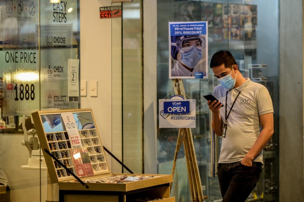 A worker uses his phone as he stand in front of an eyeglasses store at a mall in Quezon City, Philippines on August 27, 2020. (Photo: Lisa Marie David/NurPhoto via Getty Images)