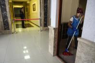 A Russian Federal Bailiffs Service officer guards a corridor leading to a courtroom as a janitor washes the floor inside the court in Yekaterinburg, Russia, Thursday, July 18, 2024, during a hearing of Wall Street Journal reporter Evan Gershkovich's suspected spying activities. (AP Photo/Dmitri Lovetsky)