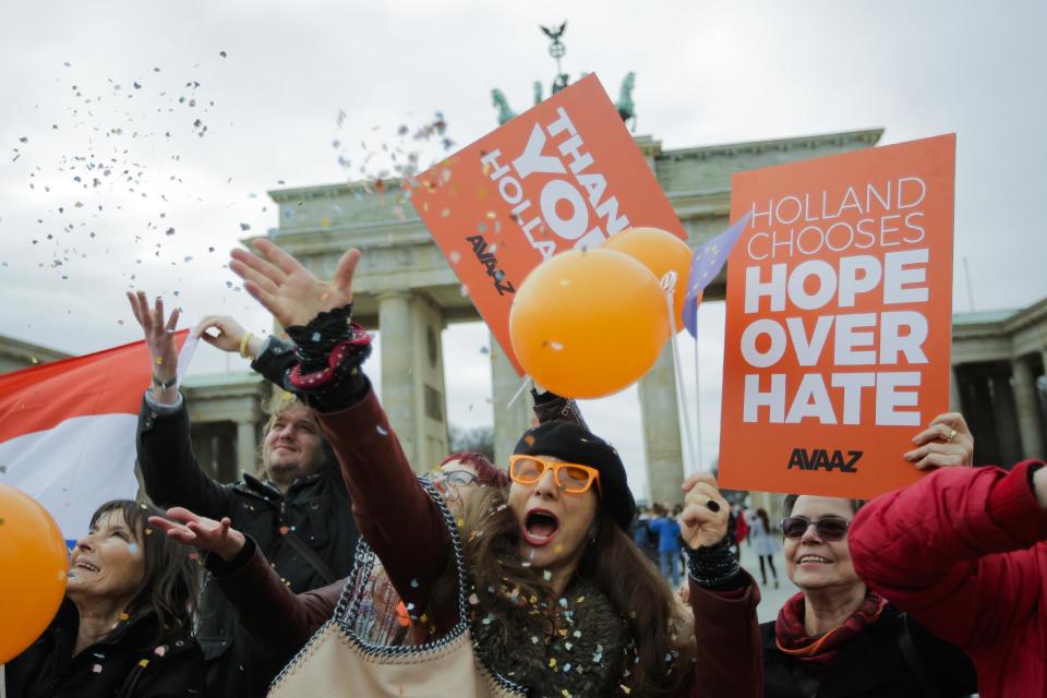 Activists of the AVAAZ network celebrate the election results in the Netherlands in front of the Brandenburg Gate in Berlin, Germany, Thursday, March 16, 2017. (AP Photo/Markus Schreiber)
