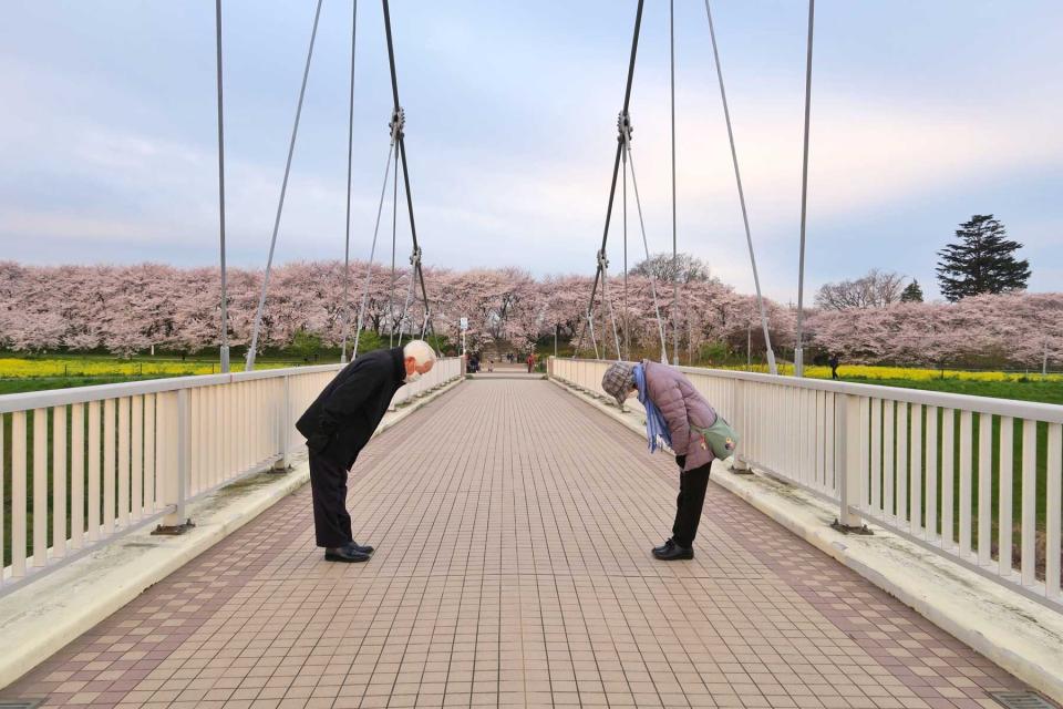 Two people in masks bowing to each other in Japan