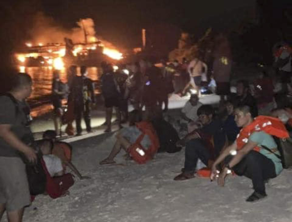 In this photo provided by the Philippine Coast Guard, survivors rest after being rescued from the still burning MV Lady Mary Joy at Basilan, southern Philippines early Thursday March 30, 2023. More than a dozen people died while other were reported missing after an inter-island cargo and passenger ferry with about 200 passengers and crew onboard caught fire close to midnight in the southern Philippines, a provincial governor said Thursday. (Philippine Coast Guard via AP)