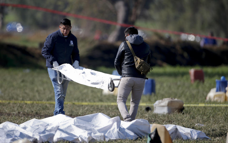 Forensic experts move a body with several in bodybags near them. Source: AP