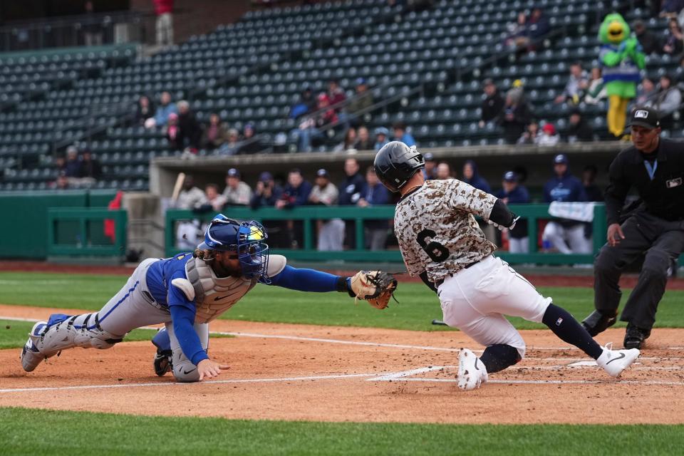 Apr 3, 2024; Columbus, OH, USA; Columbus Clippers outfielder Lorenzo Cedrola (6) scores past Omaha Storm Chasers catcher Logan Porter (16) during Opening Day at Huntington Park.