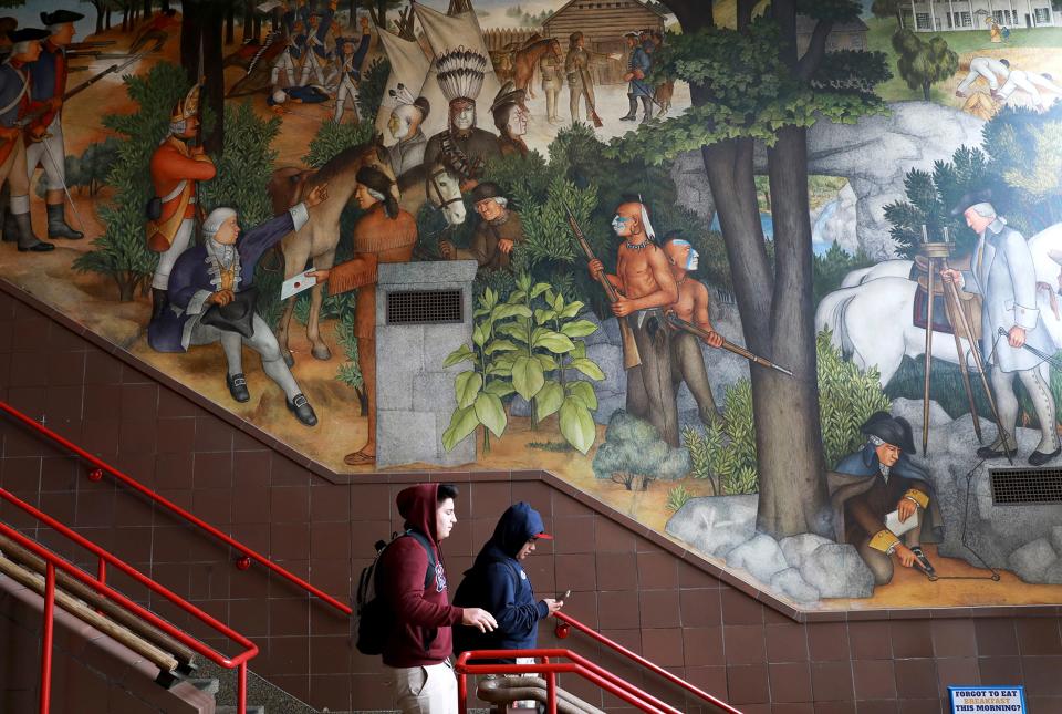 In this photo taken April 3, 2019, a pair of students walk past a historic mural that includes slaves and a dead Native American at George Washington High School in San Francisco. The San Francisco school board unanimously voted Tuesday, June 25, 2019, to destroy a controversial mural displayed in a public high school.