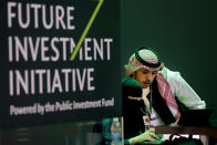 FILE - In this Oct. 22, 2018, file photo, Saudi employees print badges of participants of the Future Investment Initiative in Riyadh, Saudi Arabia. Lured by a long-looming stock offering of Saudi Arabia's massive state-run oil company, investors and business leaders have returned to the kingdom's capital for an investment forum overshadowed last year by the assassination of Washington Post columnist Jamal Khashoggi. (AP Photo/Amr Nabil, File)