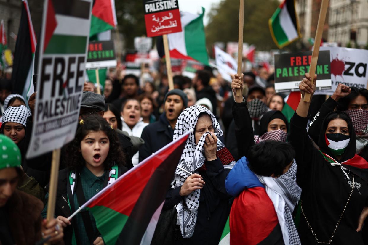 People hold up placards and wave Palestinian flags in Parliament Square after taking part in a 'March For Palestine' in London on October 28, 2023, to call for a ceasefire in the conflict between Israel and Hamas. Thousands of civilians, both Palestinians and Israelis, have died since October 7, 2023, after Palestinian Hamas militants based in the Gaza Strip entered southern Israel in an unprecedented attack triggering a war declared by Israel on Hamas with retaliatory bombings on Gaza. (Photo by HENRY NICHOLLS / AFP) (Photo by HENRY NICHOLLS/AFP via Getty Images)