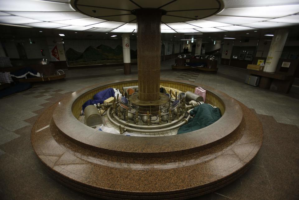 Homeless men snuggle in sleeping bags inside an unused fountain and on bench seats at an underground passage near Sendai Station in Sendai, northern Japan December 17, 2013. (REUTERS/Issei Kato)