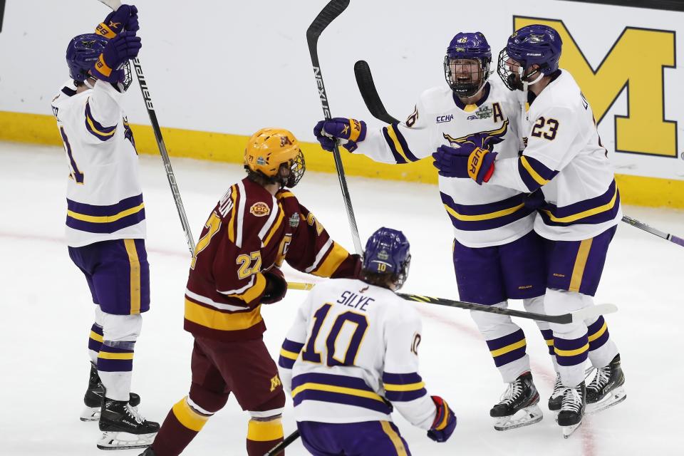 Minnesota State's Reggie Lutz (16) celebrates his goal with Jake Livingstone (23) as Minnesota's Blake McLaughlin (27) skates past during the second period of an NCAA men's Frozen Four college hockey semifinal Thursday, April 7, 2022, in Boston. (AP Photo/Michael Dwyer)