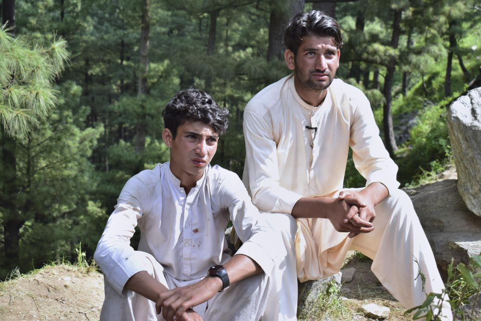 Abrar Ahmed, left, a survivor of cable car incident, sits with his cousin as he talks to members of media, near the incident site, in Pashto village, a mountainous area of Battagram district in Pakistan's Khyber Pakhtunkhwa province, Wednesday, Aug. 23, 2023. The rescue of six school children and two adults who were plucked from a broken cable car that was dangling precariously hundreds of meters (yards) above a steep gorge was a miracle, a survivor said Wednesday. The teenager said he and the others felt repeatedly that death was imminent during the 16-hour ordeal. (AP Photo/Saqib Manzoor)