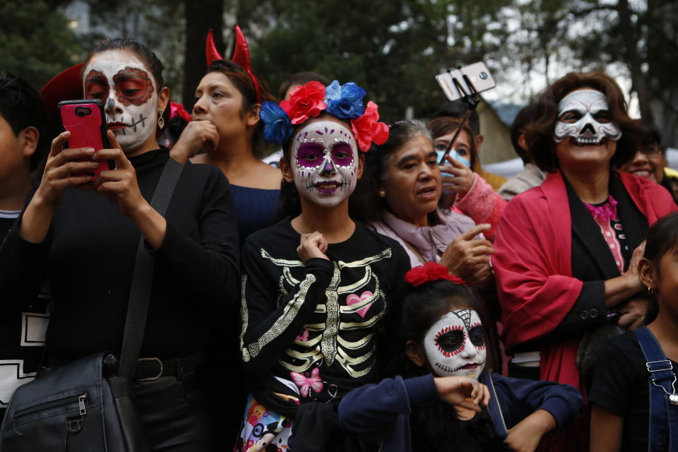 People attend the Catrinas parade down Mexico City's iconic Reforma avenue during celebrations for the Day of the Dead in Mexico, Saturday, Oct. 26, 2019. (AP Photo/Ginnette Riquelme)