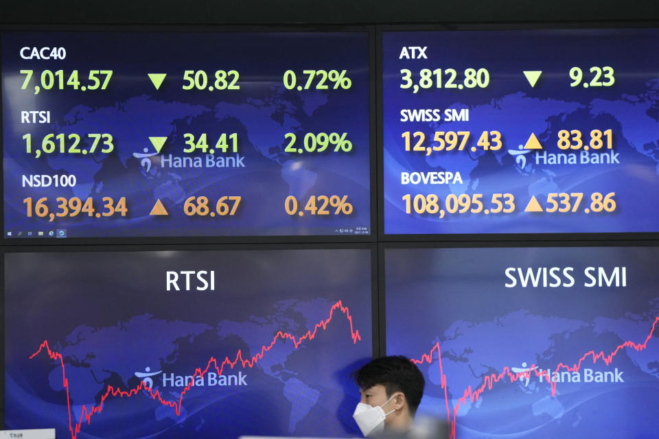 A currency trader walks by screens at a foreign exchange dealing room in Seoul, South Korea, Thursday, Dec. 9, 2021. Asian stock markets followed Wall Street higher Thursday as investors waited for U.S. inflation data that might influence the Federal Reserve's decision on when to roll back economic stimulus. (AP Photo/Lee Jin-man)