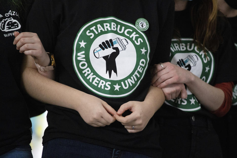 FILE - Starbucks employees and supporters link arms during a union election watch party Dec. 9, 2021, in Buffalo, N.Y. Starbucks says it’s committed to bargaining with unionized workers and reaching labor agreements next year. The move Friday is major reversal for the coffee chain after two years fighting the unionization of its U.S. stores. (AP Photo/Joshua Bessex, File)