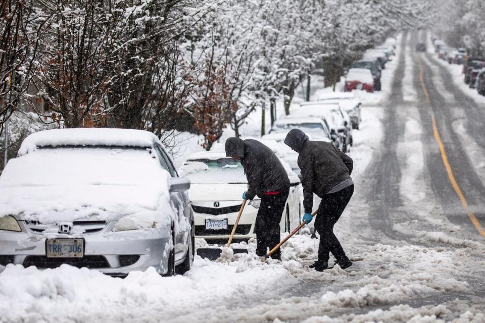 People are pictured digging out a car during a period of snowfall in Vancouver on Feb. 28, 2023. (Ben Nelms/CBC - image credit)