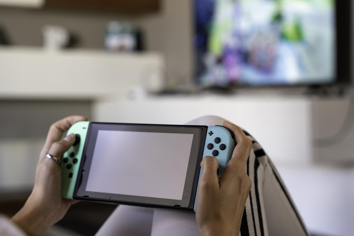 young woman playing at home with Nintendo Switch special edition - selective focus