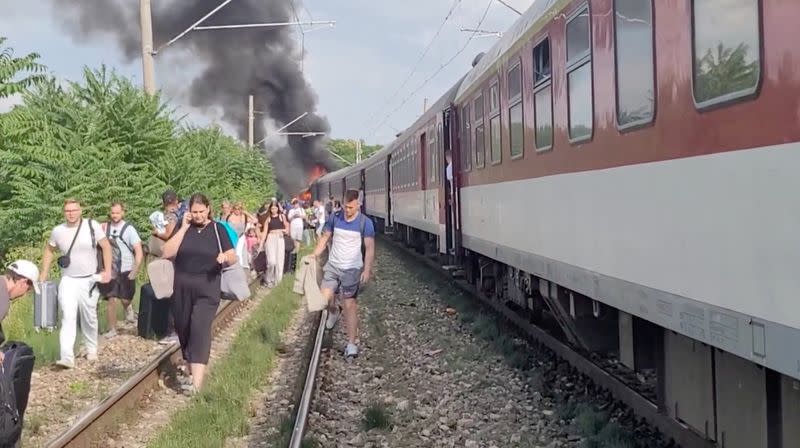Smoke billows from a fire while people evacuate from a train, near Nove Zamky