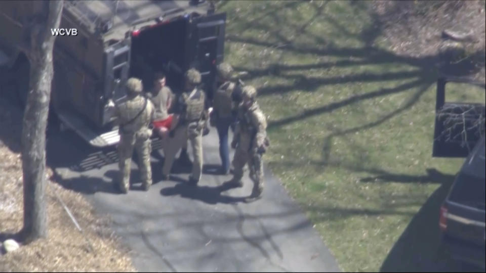 This image made from video provided by WCVB-TV, shows Jack Teixeira, in T-shirt and shorts, being taken into custody by armed tactical agents on Thursday, April 13, 2023, in Dighton, Mass. (WCVB-TV via AP)