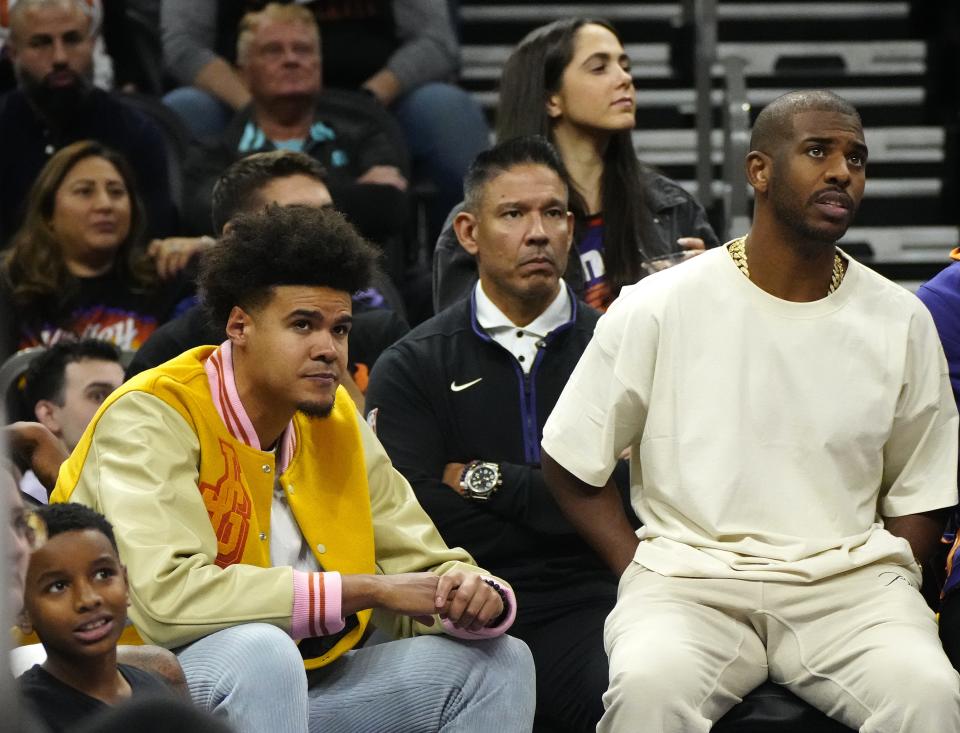 November 25, 2022; Phoenix, Ariz; USA; Suns wing Cam Johnson (L) and Chris Paul (in beige) sit on the bench watching the team take on the Pistons during a game at the Footprint Center.