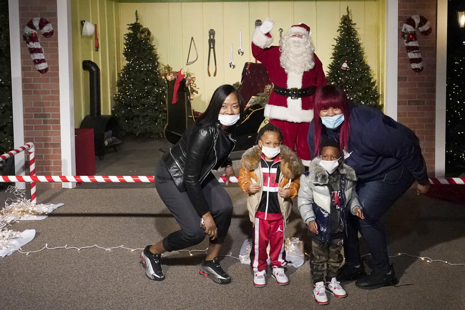 The Bell family poses for a photo with a social distant Santa as they visit Santa's Garage on the roof of a parking deck near Soldier Field in Chicago on Dec. 10, 2020. In this socially distant holiday season, Santa Claus is still coming to towns (and shopping malls) across America but with a few 2020 rules in effect. (AP Photo/Charles Rex Arbogast)