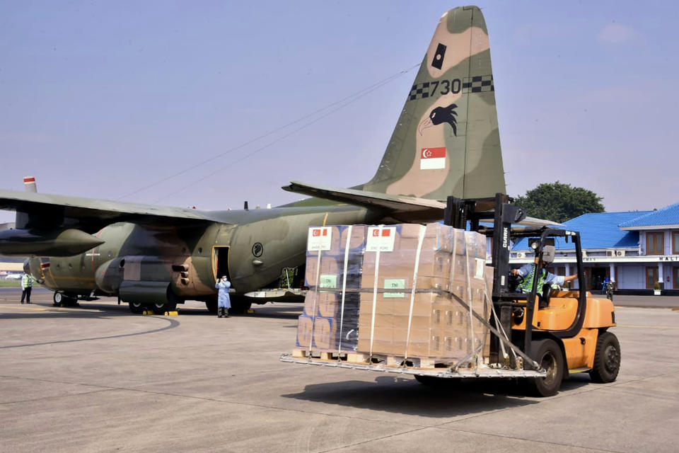 In this photo released by Indonesian Armed Forces, a military personnel uses a forklift to unload relief goods from a Singaporean Air Force cargo plane at Halim Perdanakusuma Airbase in Jakarta, Indonesia, Friday, July 9, 2021. The world's fourth most populous country is running out of oxygen as it endures a devastating wave of coronavirus cases and the government is seeking emergency supplies from other countries, including Singapore and China. (Indonesian Armed Forces via AP)