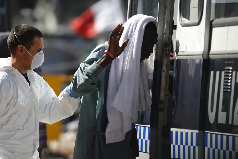 A rescued migrant walks to a police bus at the AFM Maritime Squadron base at Haywharf in Valletta's Marsamxett Harbour