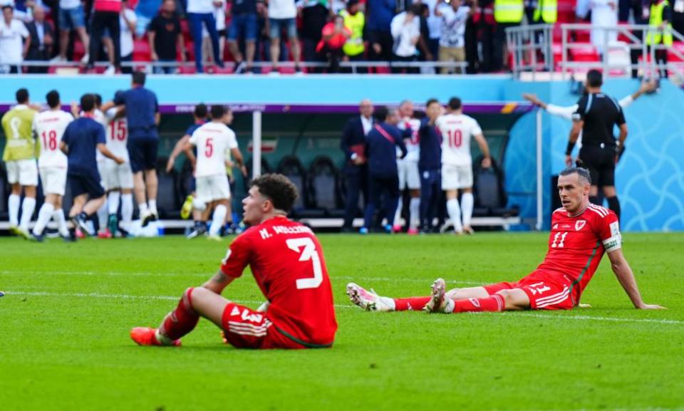 A dejected Neco Williams and Gareth Bale sit on the turf after Wales’s dramatic, devastating defeat to Iran.