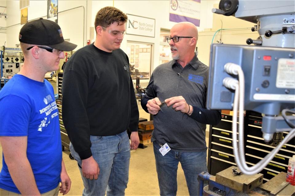 RAMTEC instructor Jim Simmering (at right) talks with students Colin Hillman and Bryston Martin about using a machine in the shop at ACWHCC.