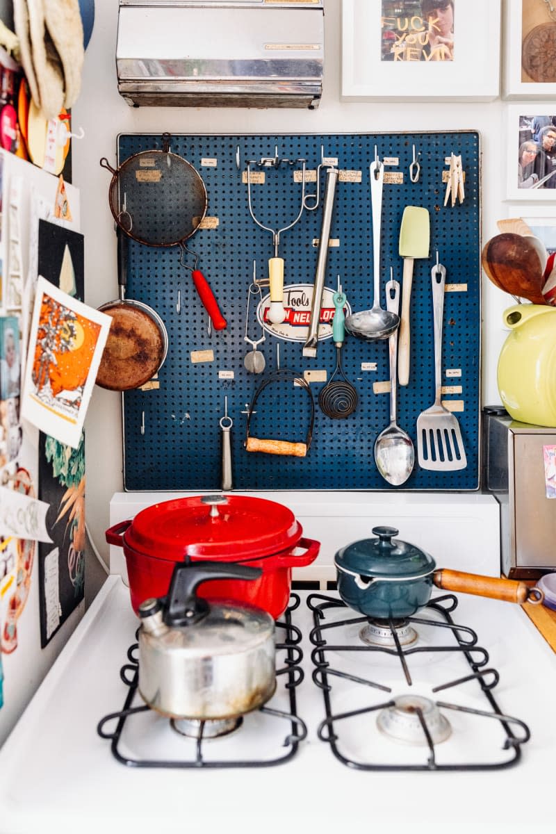 Blue peg board with kitchen utensils.