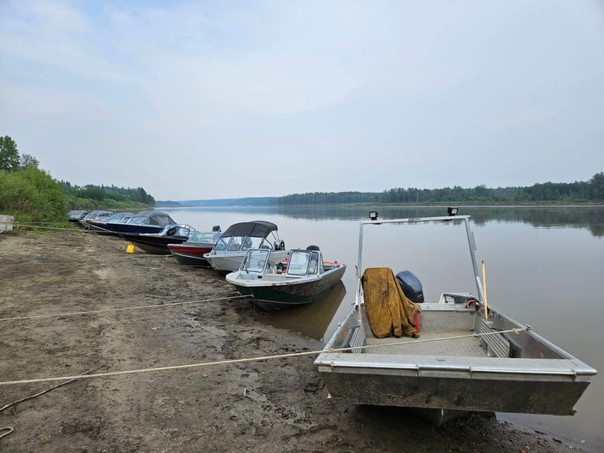 A row of boats line the banks of the Athabasca River Thursday as evacuees from Fort Chipewyan arrive.  (Nathan Gross/CBC - image credit)