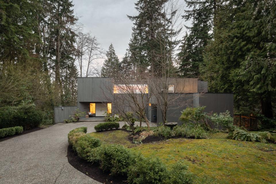 Sporting a sleek gray facade, the cedar-clad home effortlessly blends into its forest setting.